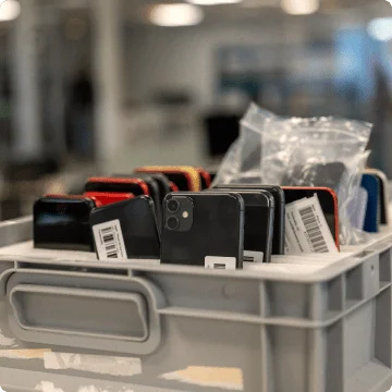 Une boîte avec des smartphones d'occasion. Ils ont été alignés debout dans des compartiments prévus à cet effet. On peut voir soit la face avant, soit la face arrière.